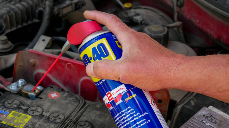 Mechanic spraying WD-40 on battery terminals