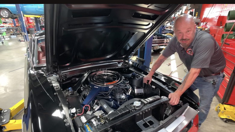 Person looks at camera showing under the hood of a 1967 Ford Mustang Fastback