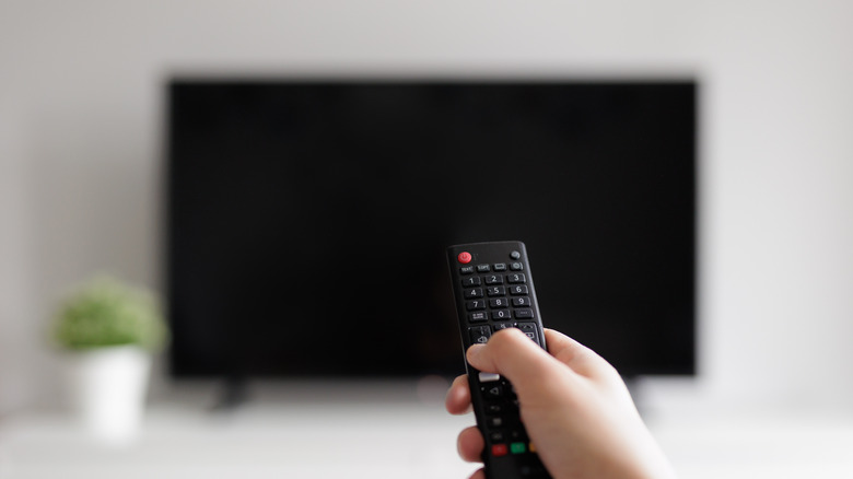 Hand holding remote pointing to off TV