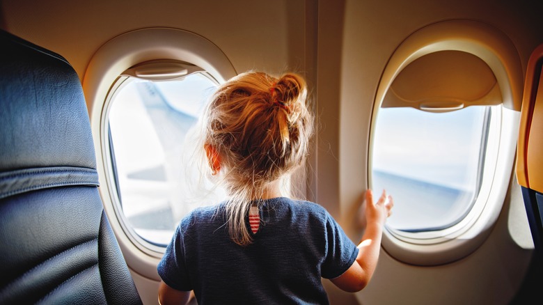 Small child looking outside of a plane window during flight