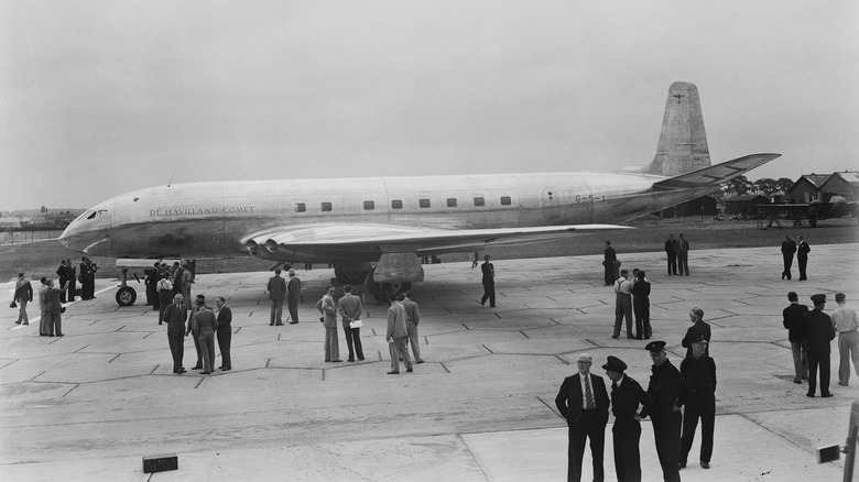 People standing in front of a De Havilland Comet on a runway