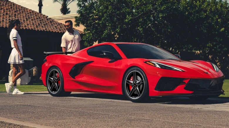 Chevrolet Corvette C8 Stingray parked with two people in background, front-right three-quarter view