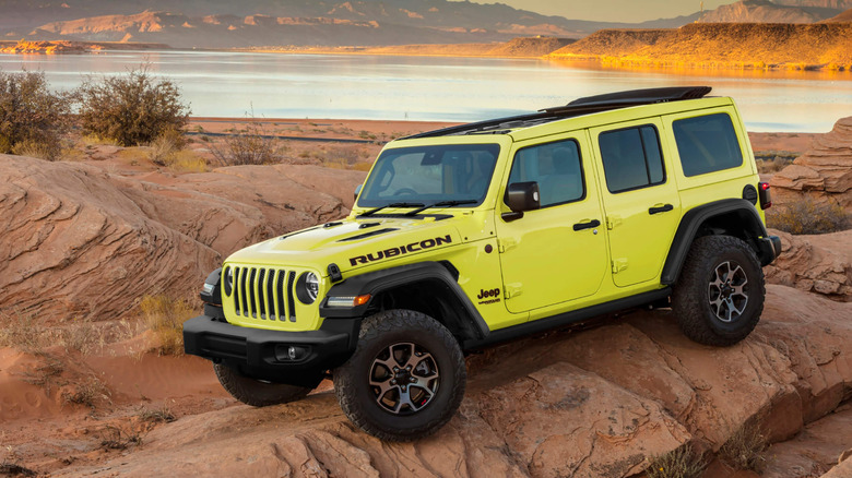 Japanese-spec 2023 Jeep Wrangler Rubicon parked on rock formation, front-left three-quarter view