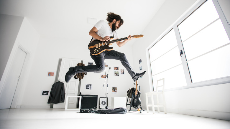 jumping while playing guitar in white room