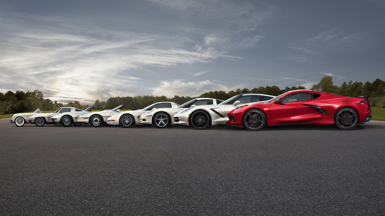 Side view of 8 generations of Corvettes with mid-engine C8 in foreground on paved lot