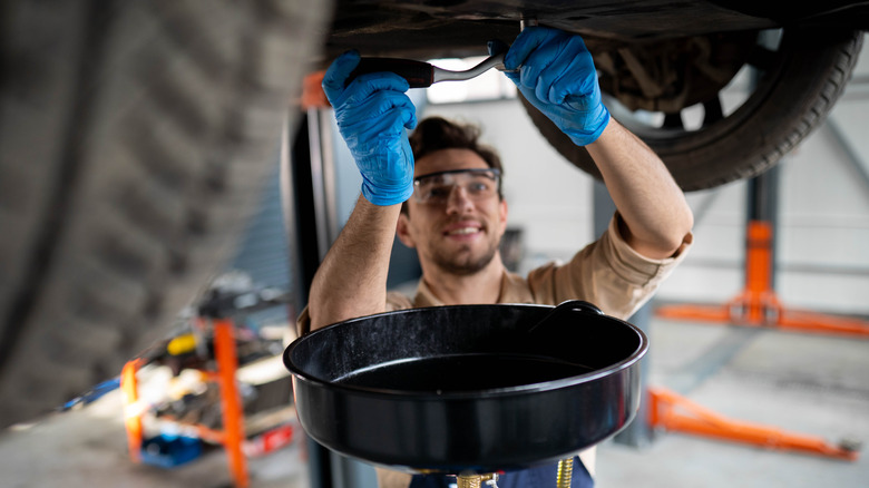 A mechanic loosening the drain plug on an oil pan