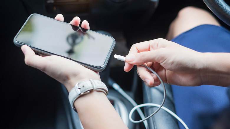 person connecting their phone to the car using a USB cable for charging and Android Auto