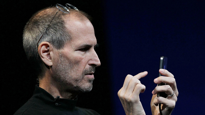 Steve Jobs looks at a phone