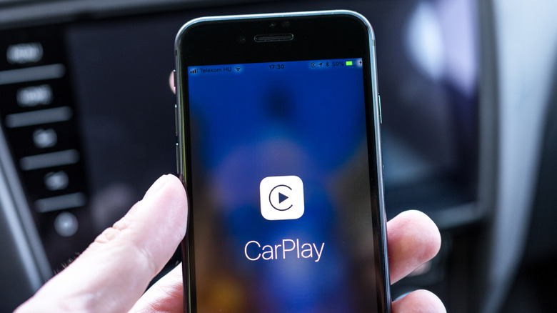 A person holding and iPhone with CarPlay displayed on it