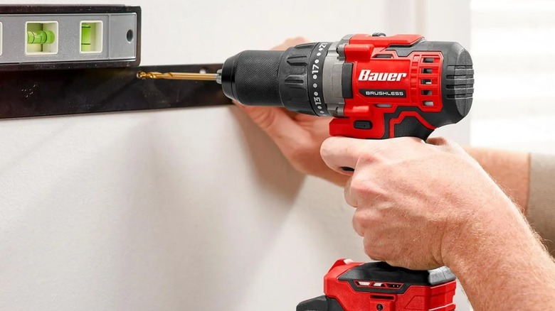 Bauer power drill driving a screw into a wall