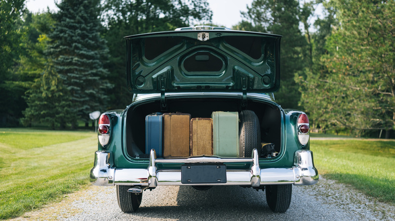 vintage car trunk open and containing suitcases.