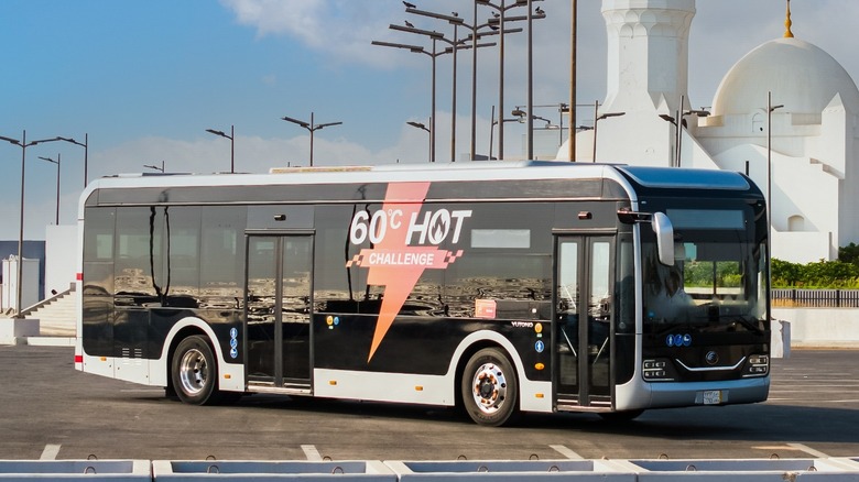 Chinese Yutong E-Bus parked in lot with mosque in background, front-right view