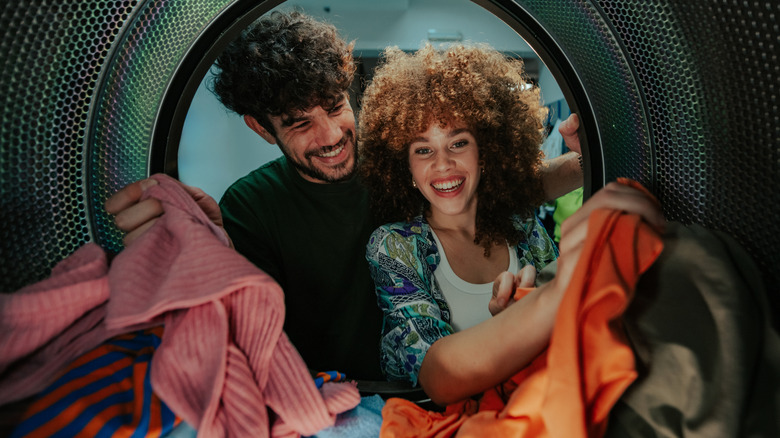Happy couple looking into clothes dryer.