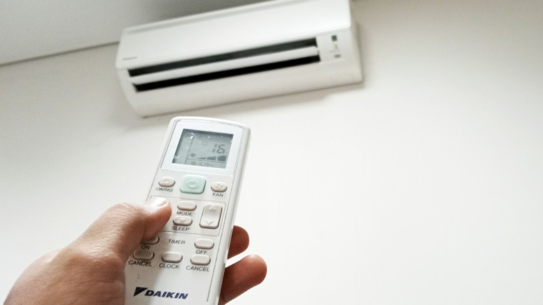 Hand holding a remote for the Daikin air conditioner in the background