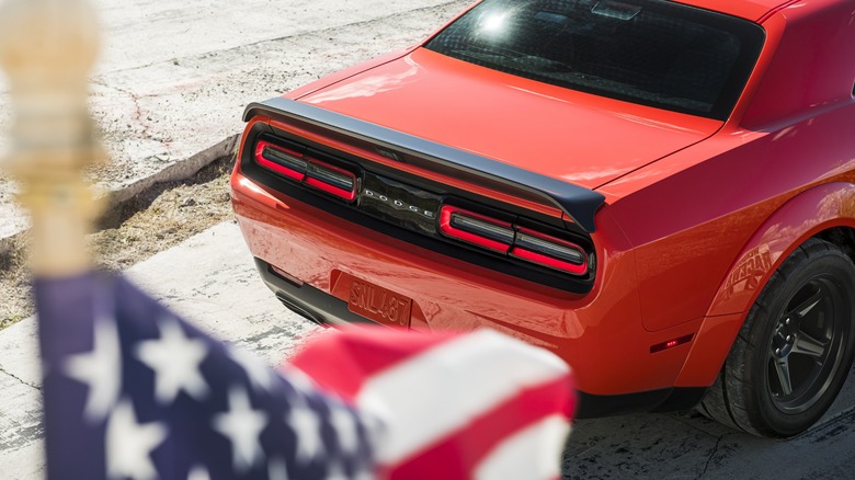 Rear view of Dodge Challenger SRT Super Stock, an out of focus American flag in the foreground