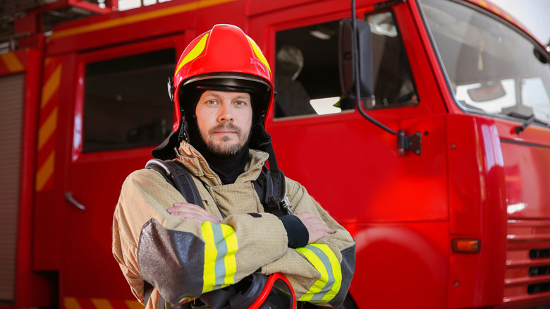 A firefighter standing in front of a red fire truck.