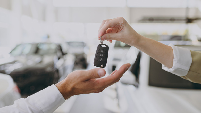 close-up of one person's hand placing a key fob into another person's hand