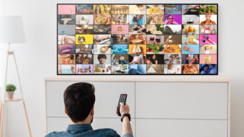 Man pointing remote at TV displaying pictures