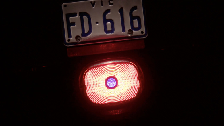 an illuminated harley red tail light with a blue lens