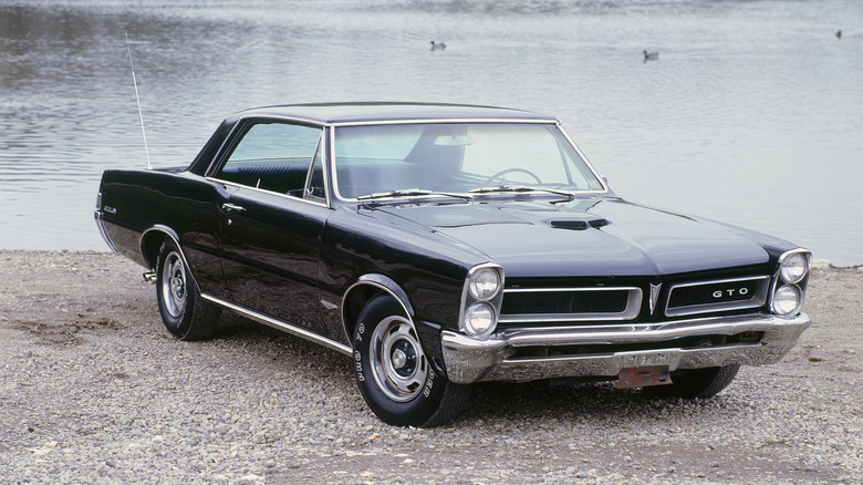 Black 1965 Pontiac GTO parked by lake, front 3/4 view