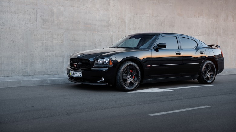 A black Dodge Charger RT sedan in front of concrete wall.