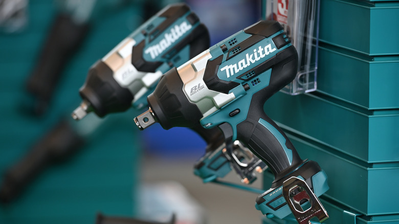 A pair of electric Makita drills hanging on a wall