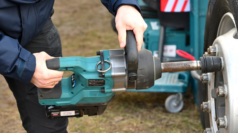 A worker using a Makita impact wrench to unscrew a wheel nut