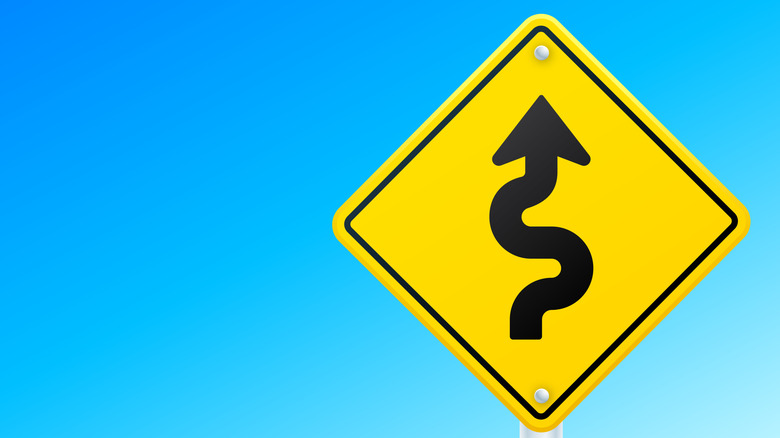 Yellow traffic sign indicating a winding road ahead.