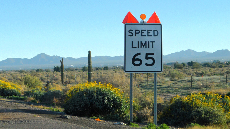 65 MPH speed limit sign on the side of a highway in the desert.