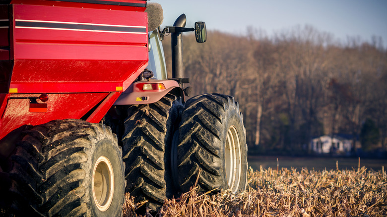 A red tractor and grain wagon sitting in a freshly harvested corn field