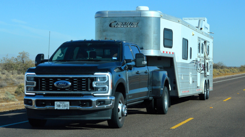 A pickup truck hauls a fifth wheel camper trailer on the highway