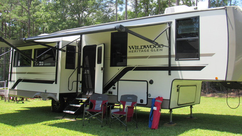 A fifth wheel camper trailer parked on the grass.