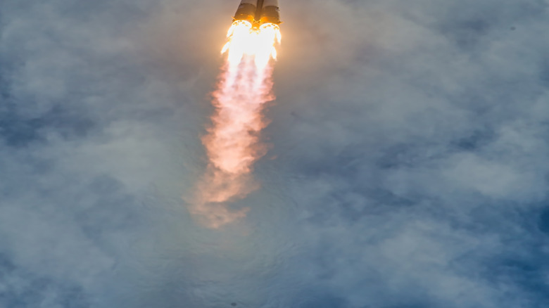 A NASA rocket flying toward the clouds.