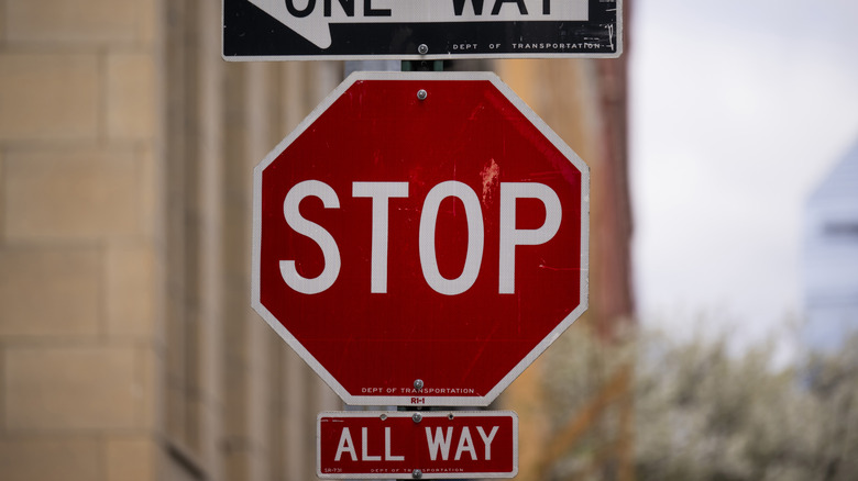 Close up of a stop sign with other traffic signs on a post.