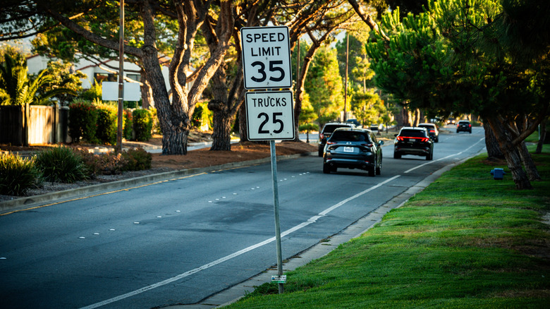 Two different speed limit signs on top of each other in a residential neighborhood