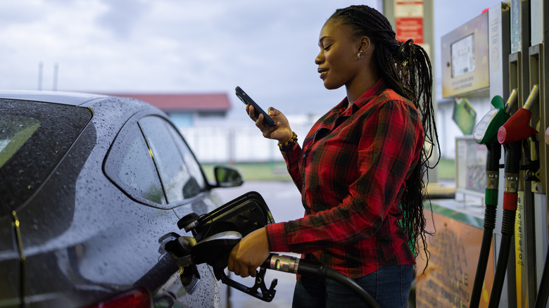 Person filling up tank while on phone