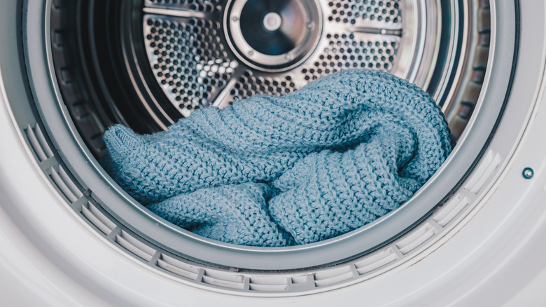close-up of a blue sweater sitting in the tub of a front-loading washing machine
