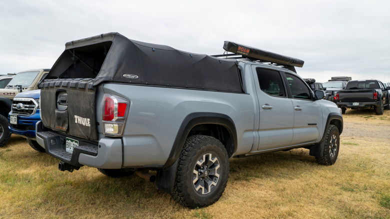 Gray Toyota Tacoma pickup truck with various accessories parked on grass