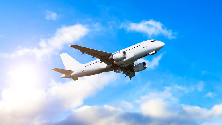 Airplane in the flight, travel background with airplane flying in the blue sky over the clouds.