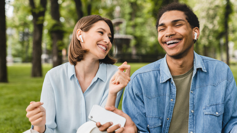 Two young people listening to music with earbuds in the park.