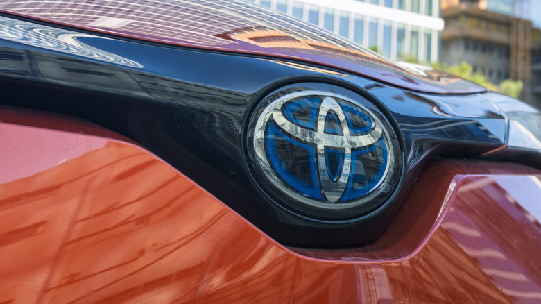 Close up view of blue hybrid Toyota emblem on orange Toyota CH-R.