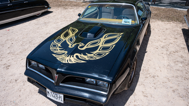 A black second-generation Pontiac Firebird Trans Am parked on dirt