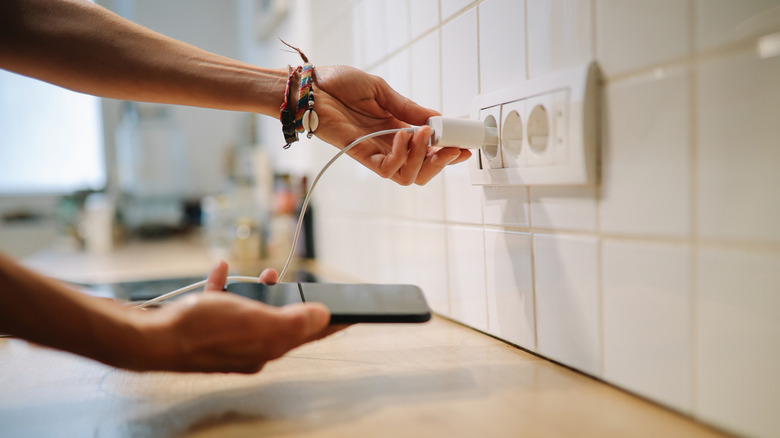 Person plugging a phone charger into the wall