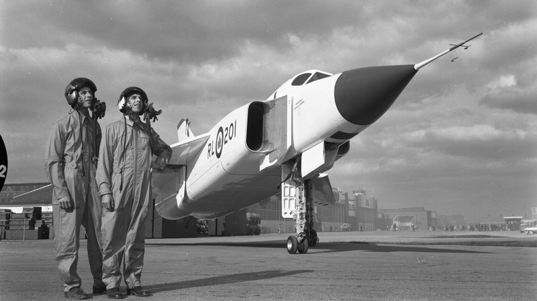 Two pilots stand beside the Avro Arrow in 1957.