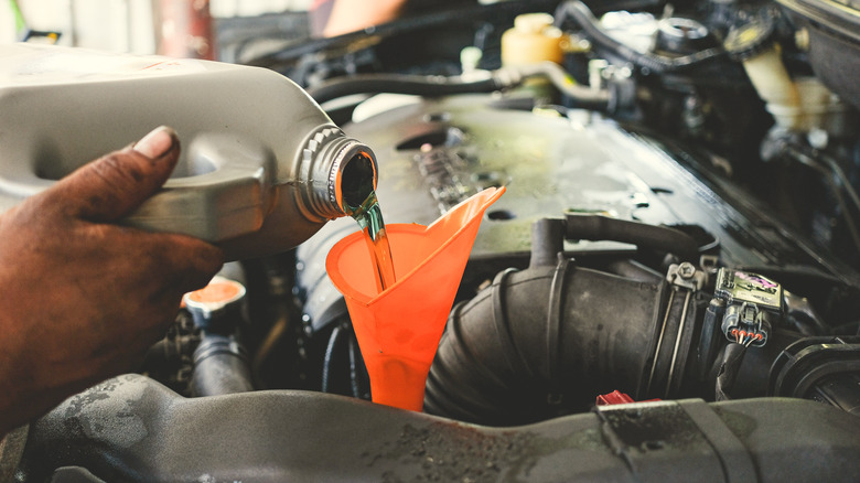 Close of up hands pouring transmission oil through a funnel