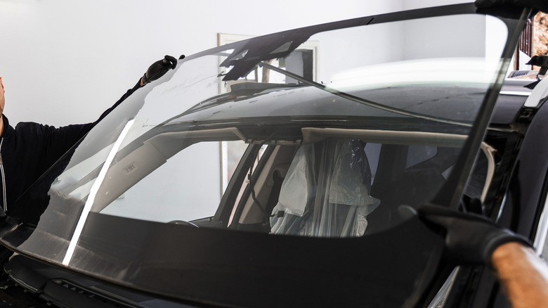 technician installing new windshield on a black car