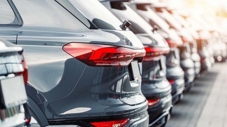 A row of new cars in a dealership parking lot