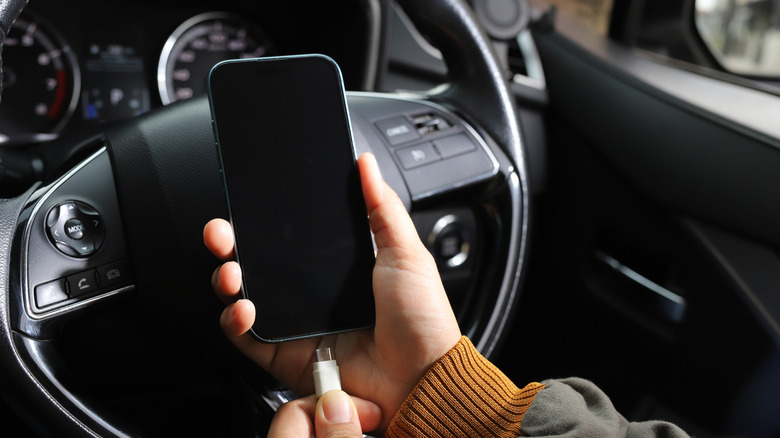 A man plugging his cell phone into his car via USB