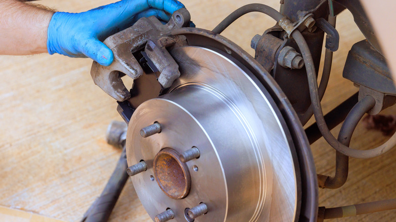 A person handling a car's brake caliper