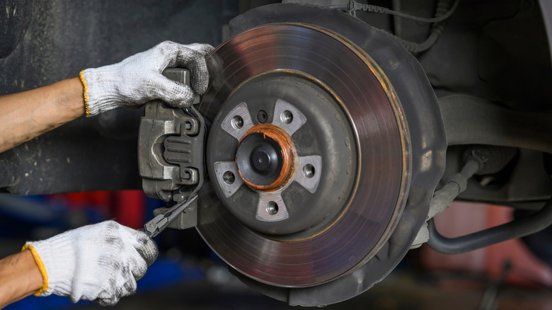 A mechanic working on brake pads on a vehicle.